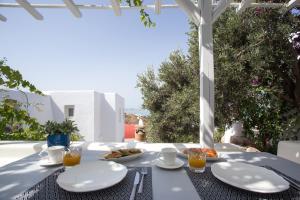 a table with plates of food on a white table cloth at Flaskos Village Fanari in Mýkonos City