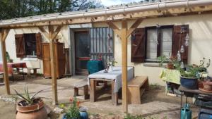 un patio con una mesa y una casa con macetas en Lovely 2-Bed shepherds hut in a Forest, en Sougères-en-Puisaye