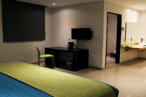 Dormitorio con cama, escritorio y TV en Mision Express Xalapa Centro, en Xalapa