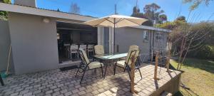a table and chairs with an umbrella on a patio at DullVino First House in Dullstroom