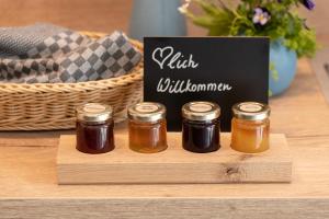 文西德的住宿－BLEIBE4 Ferienwohnungen，一张桌子上装有四罐蜂蜜的木托盘
