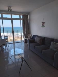 - un salon avec un canapé et une table en verre dans l'établissement 86 windermere self catering apartments, à Durban