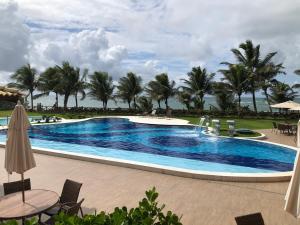 a pool at the resort with palm trees in the background at Guarajuba - Genipabu Summer House (Flat beira mar) in Camaçari