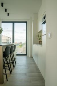 a kitchen with chairs and a counter with a window at Ostend Port Side incl parking in Ostend