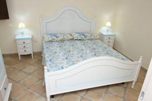 um quarto com uma cama branca com duas mesas de cabeceira em Villa Elisa residenza Agorà Villasimius em Villasimius