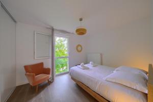 a bedroom with a bed and a chair and a window at La Carasse in Lège-Cap-Ferret
