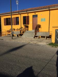 a yellow building with two benches in front of it at B&B La Torre in Rosello