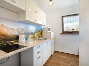 a kitchen with white cabinets and a painting on the wall at Wypoczynek Pod Skarpą in Chochołów
