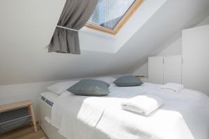 uma cama branca com almofadas azuis num quarto em Apartamenty Południowa 14 by Renters em Dźwirzyno