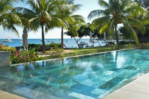 a swimming pool with palm trees and the ocean at Latitude - with private plunge pool in Rivière Noire