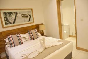 a bedroom with a bed with white sheets and a mirror at Latitude - with private plunge pool in Rivière Noire