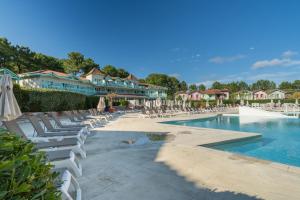 einen Pool in einem Resort mit Stühlen und Sonnenschirmen in der Unterkunft Residence Lacanau Les Pins - maeva Home in Lacanau