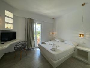 ein weißes Schlafzimmer mit Bett, Schreibtisch und Fernseher in der Unterkunft Villa veranda in Plaka