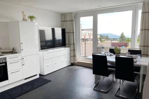 una cucina con tavolo, sedie e televisore di PENTHOUSE mitten im BAYERISCHEN WALD +NETFLIX +AUSSICHT = SUPER COZY a Sankt Englmar