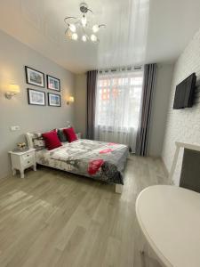 um quarto com uma cama com almofadas vermelhas e uma janela em Apartment Studio PARIS 2 em Irpin