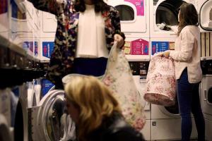 two women standing in a laundry room holding bags at Student Only Chapter Islington in London in London