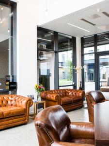 a lobby with brown leather couches and chairs at Spacious and Comfy Studios at Chapter Highbury I in London in London