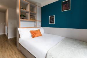 a bed with an orange pillow on it in a room at For Students Only Stoneworks in Brighton in Brighton & Hove