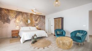 a bedroom with a white bed and two blue chairs at Etti - Paradise Rosa Maria in Pájara