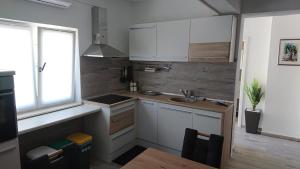 una pequeña cocina con armarios blancos y fregadero en AmAmA, en Brodarica