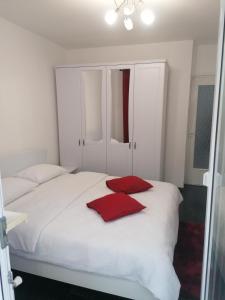 a white bed with two red pillows on it at Apartament Racadau in Braşov