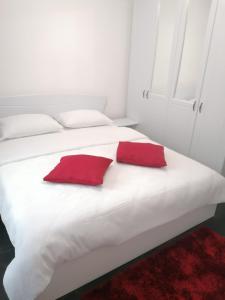 een wit bed met twee rode kussens erop bij Apartament Racadau in Braşov