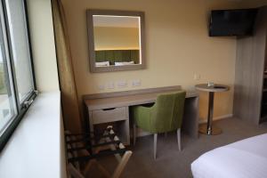 a hotel room with a desk and a mirror at Hellidon Lakes Hotel in Daventry