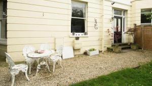 a patio with a table and chairs and a house at Lovely 3-Bed House in Cheltenham in Cheltenham