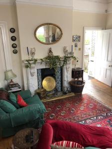 a living room with a green couch and a fireplace at Lovely 3-Bed House in Cheltenham in Cheltenham