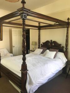 a large bed with a wooden frame and white sheets at Lovely 3-Bed House in Cheltenham in Cheltenham