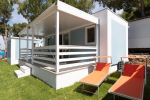 a tiny house with two chairs in a yard at Porto Pirrone Camping in Leporano