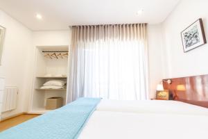 Un dormitorio con una gran cama blanca y una ventana en Apartamento Mar & Sol, en Póvoa de Varzim