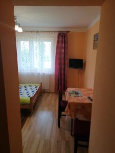Zimmer mit einem Bett, einem Tisch und einem Fenster in der Unterkunft Pokoje Pod Łukami in Solina