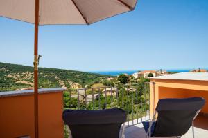 een balkon met 2 stoelen en een parasol bij Da Fe' - Casa con terrazza panoramica in Cuglieri