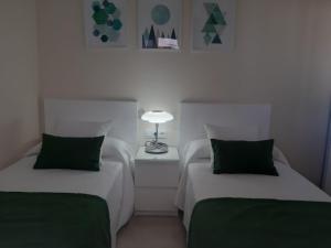 two beds with green pillows in a room at La Gomera in Gran Tarajal
