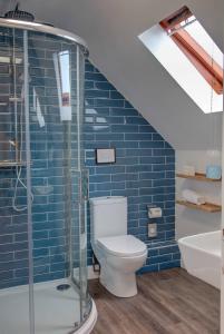a bathroom with a toilet and a blue tiled wall at The Grange at Oborne in Sherborne