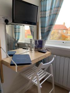 a desk with a television and a chair in front of a window at Holly Trees in Seahouses