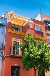 un edificio rojo con un árbol delante de él en HSH Suites Triana, en Sevilla