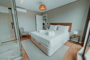 a bedroom with a large white bed and a glass door at Rooftop Marina l by Madeira Best Apartments in Funchal