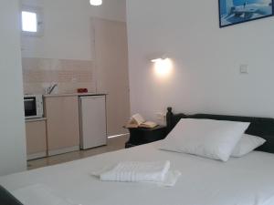 a white bed in a room with a kitchen at Chrisanthi Studios in Agios Prokopios