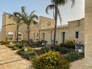 ein Gebäude mit Palmen und Blumen im Innenhof in der Unterkunft PODERE CARAFA in Nardò