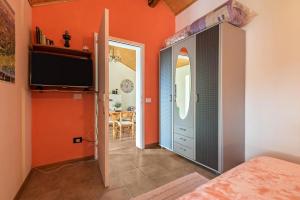 1 dormitorio con paredes de color naranja y puerta con TV en Baita Velo, en Arco