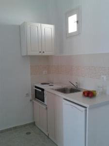a kitchen with white cabinets and a sink and a stove at Chrisanthi Studios in Agios Prokopios