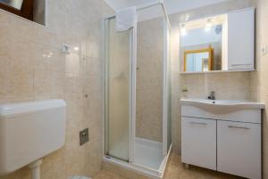 ein Badezimmer mit Dusche, Waschbecken und Spiegel in der Unterkunft Apartments Maria in Poreč