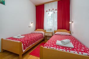 2 Betten in einem Zimmer mit roter und weißer Bettwäsche in der Unterkunft Apartments Maria in Poreč