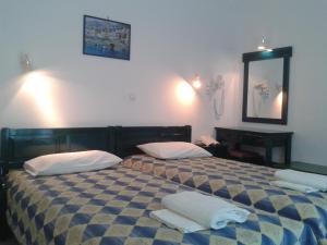 1 dormitorio con 2 camas y espejo en la pared en Chrisanthi Studios en Agios Prokopios