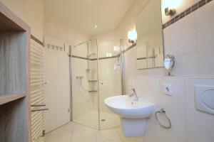 a white bathroom with a sink and a shower at Parkoase 3, Maisonette Wohnung mit Balkon in Wangerooge +14 photos