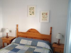 a bedroom with a wooden bed and two lamps at Apartamentos Torrelaguna in Vera +31 photos