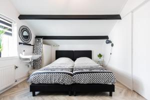 Schlafzimmer mit einem schwarzen und weißen Bett und einem Waschbecken in der Unterkunft Holiday Home Oostkapelle in Oostkapelle
