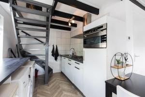a kitchen with white cabinets and a spiral staircase at Holiday Home Oostkapelle in Oostkapelle +12 photos